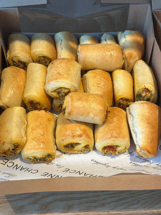 Box of golden-brown fish rolls on a cardboard surface