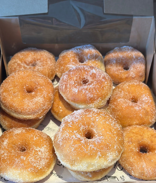 Box of sugared donuts on a wooden surface