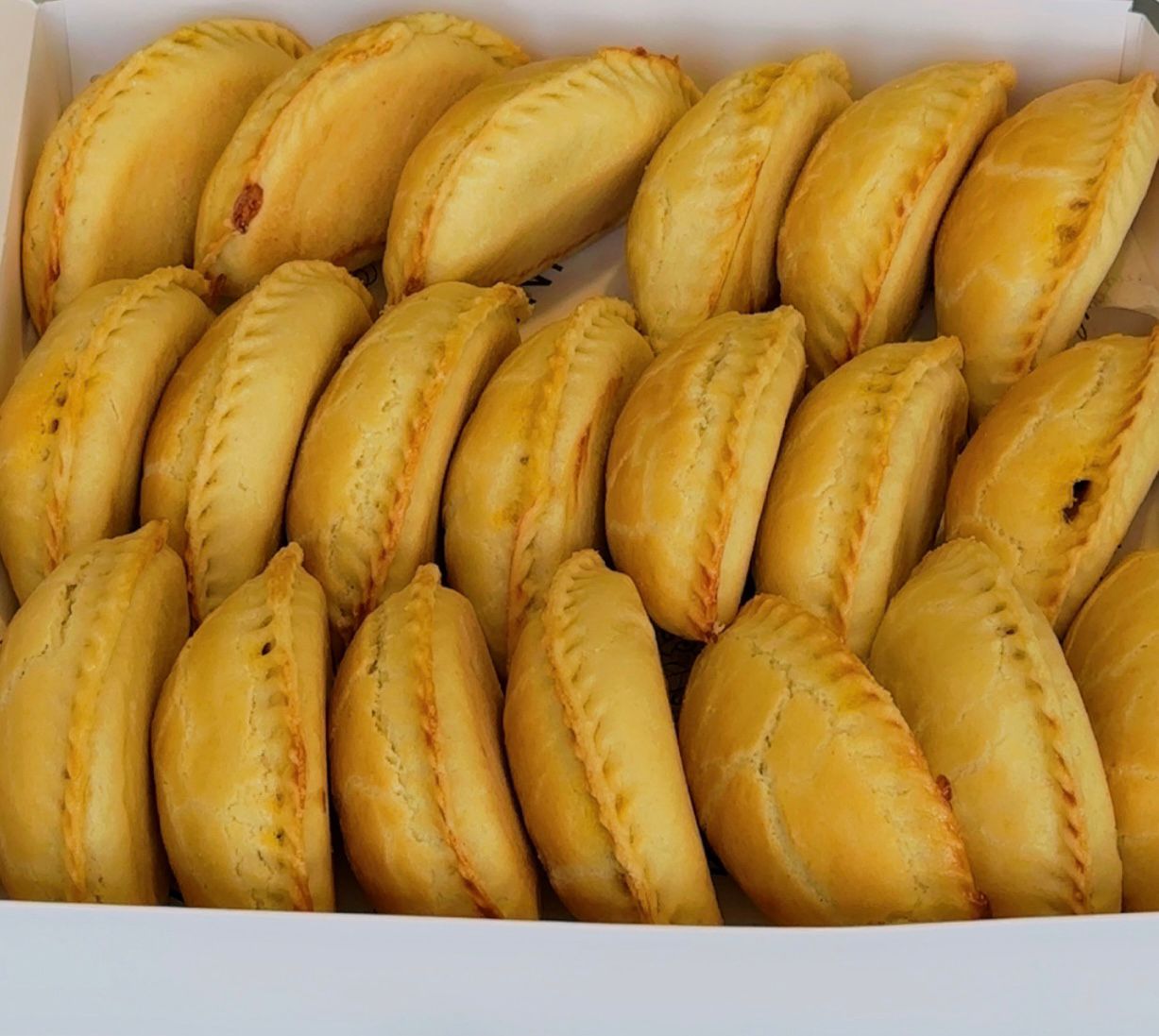 Box of golden-brown meat pies arranged neatly.